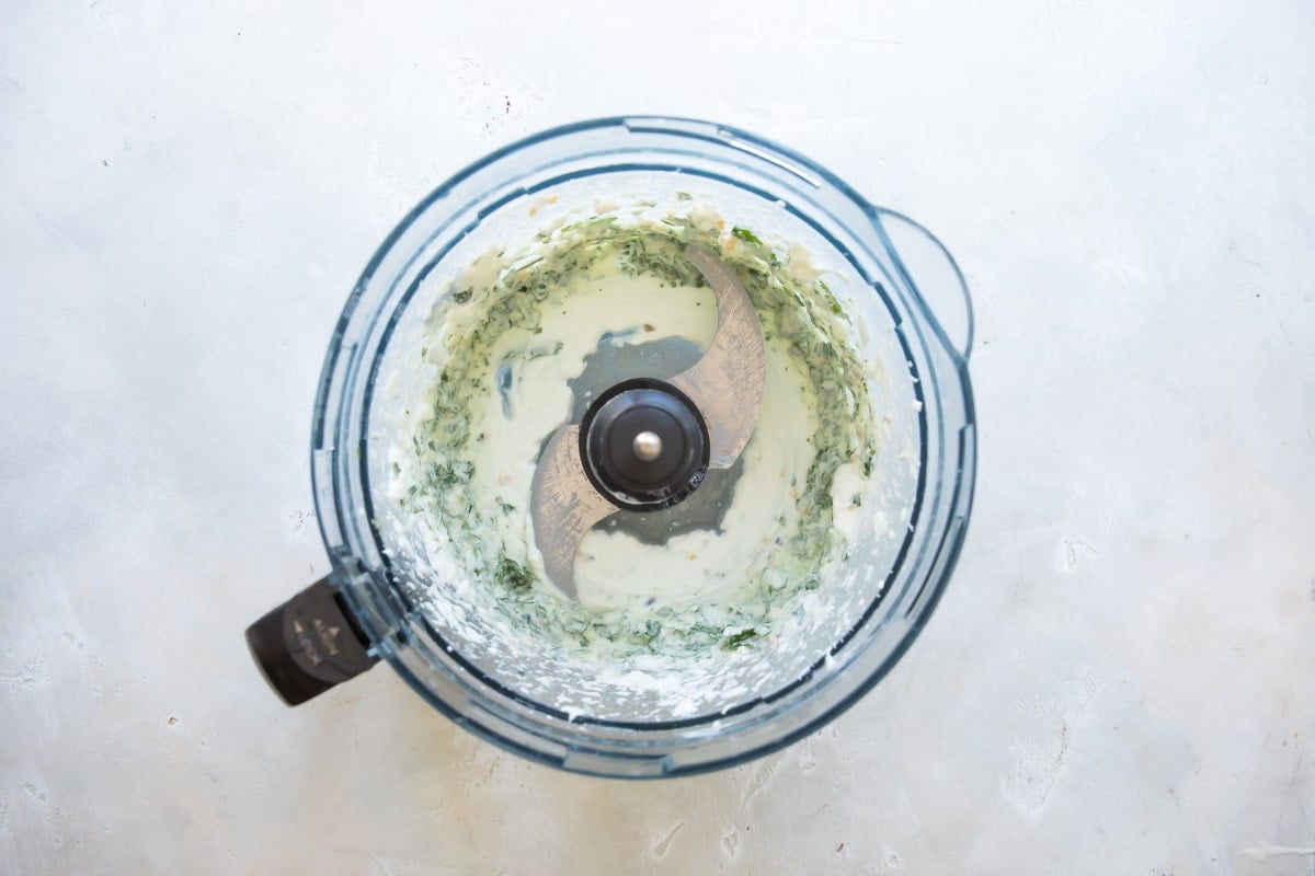 Creamy cilantro lime dressing being blended in a food processor.
