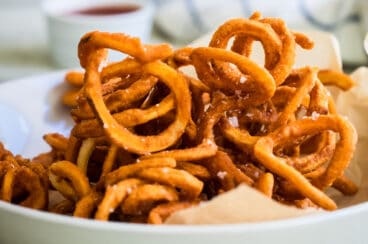 Curly fries in a white bowl.