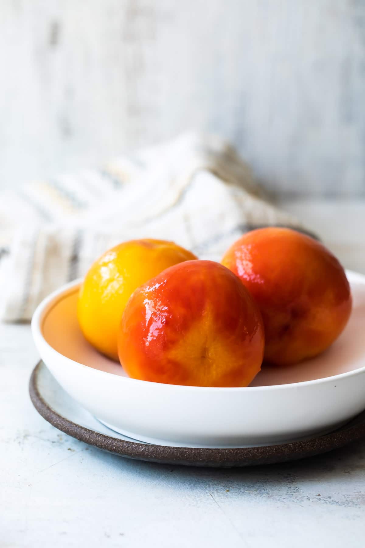 Three peaches in a white bowl.