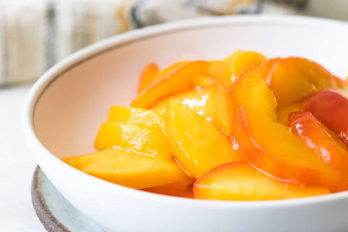 Peach slices in a white bowl.