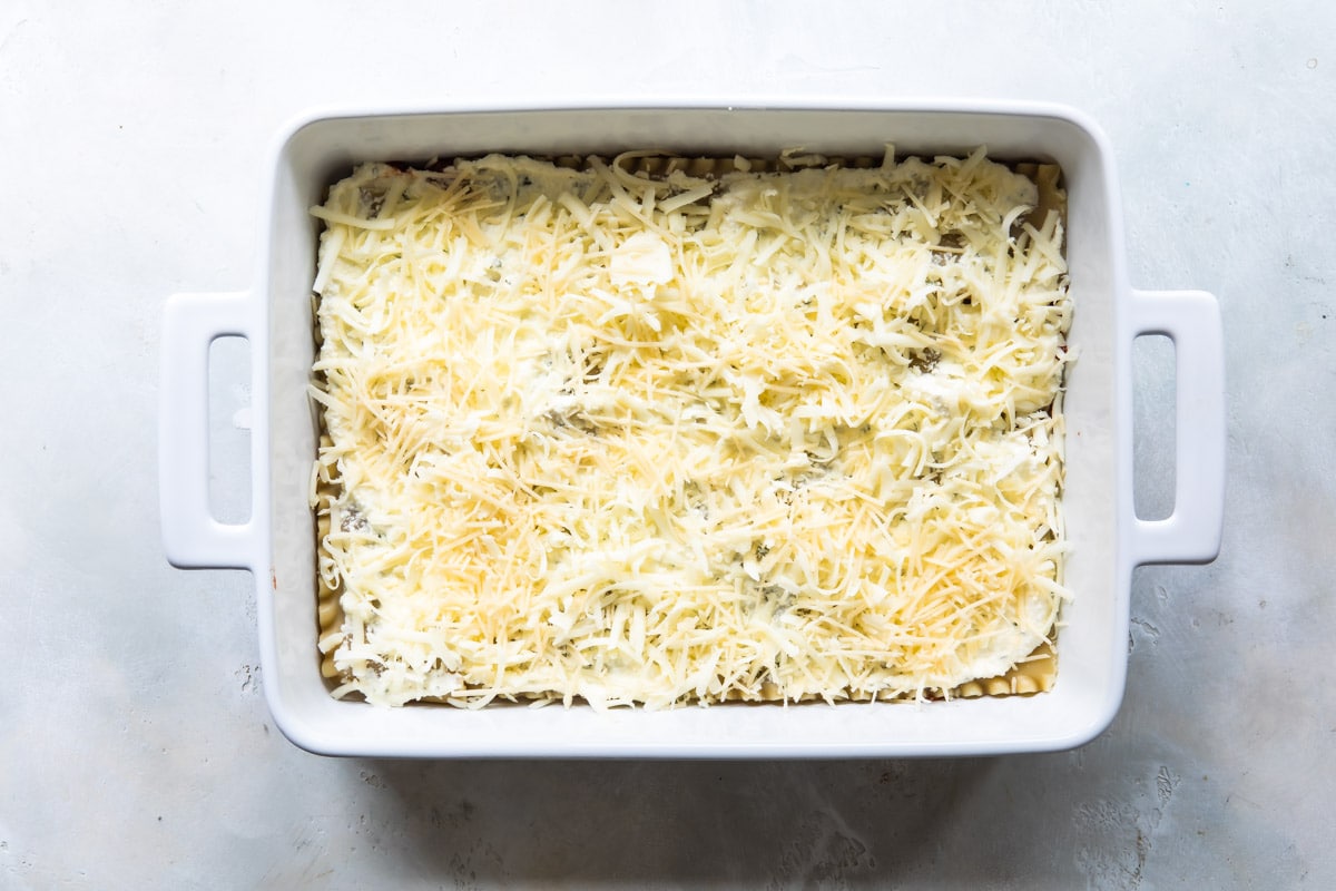 2 layers of unbaked lasagna in a baking dish.