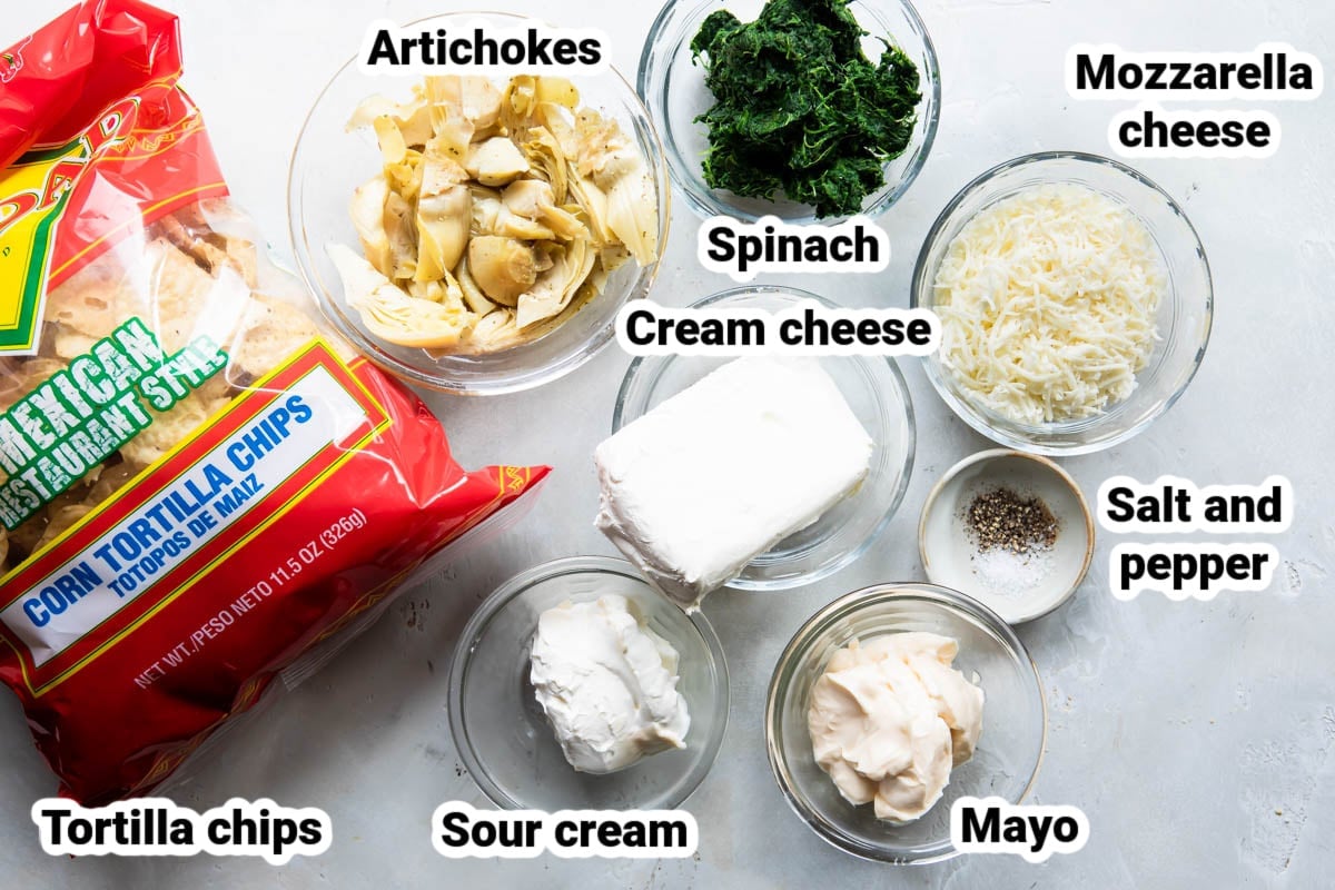 Labeled spinach artichoke dip ingredients in various bowls.