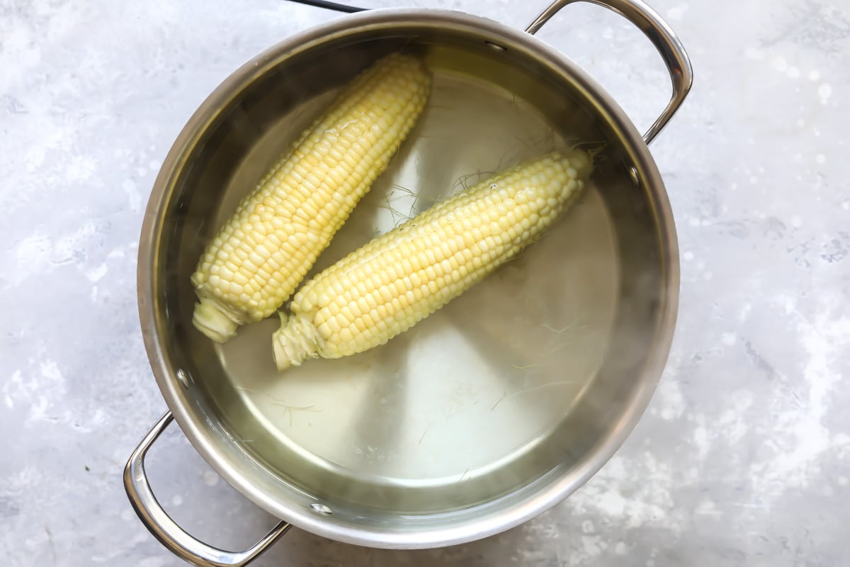 2 ears of corn in a pot of water.