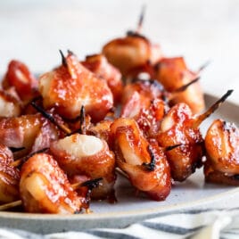 Bacon wrapped water chestnuts on a gray plate.