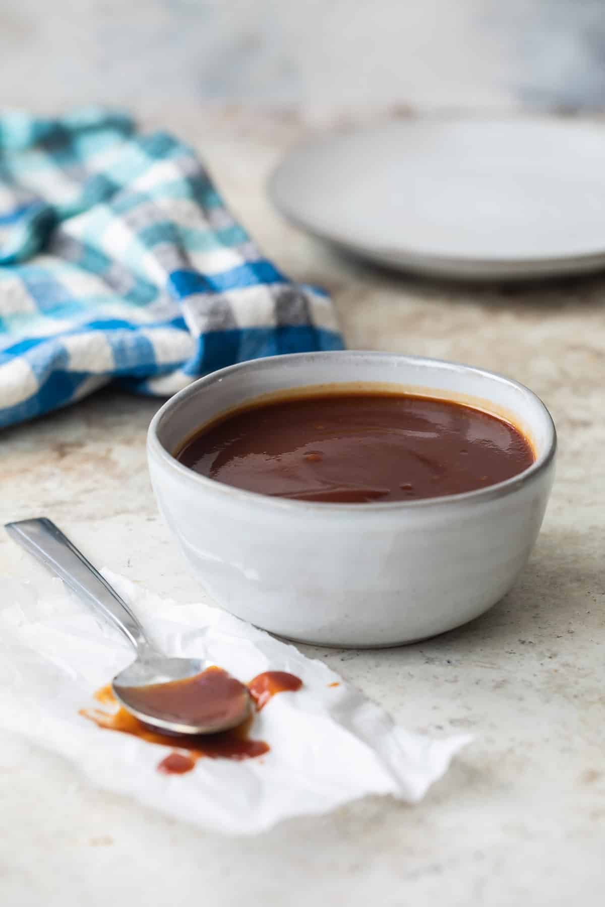 A bowl of barbecue sauce with a spoon resting next to it.