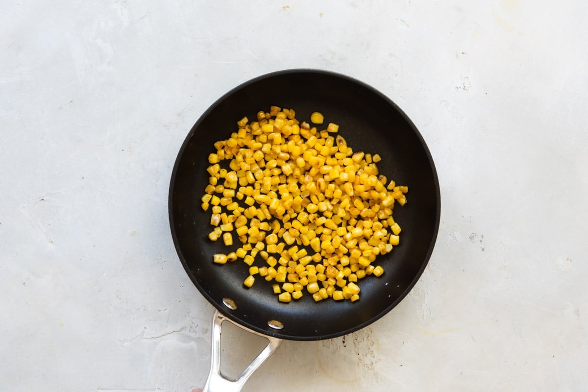 Roasted corn in a black frying pan.