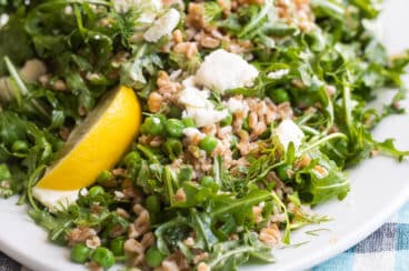 Farro salad with peas and feta on a white plate.