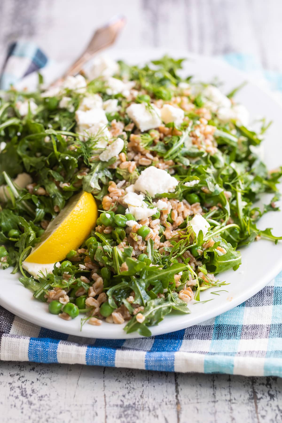 Farro salad with peas and feta on a white plate.