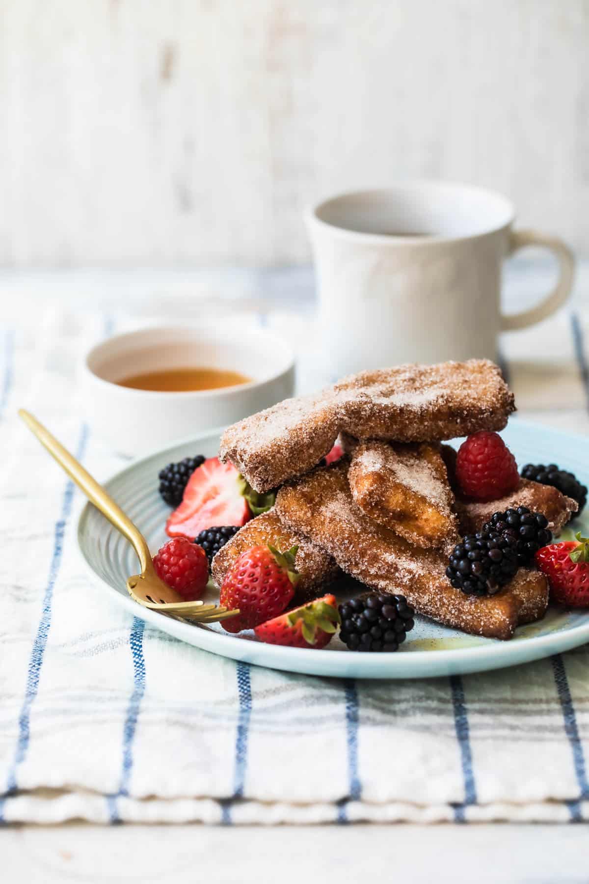 A stack of French toast sticks covered in berries on a plate.