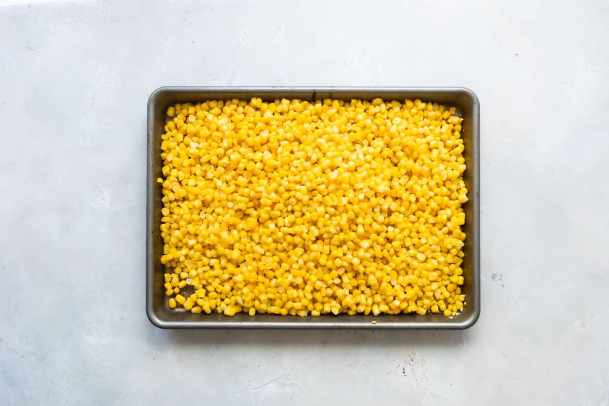 Corn on a baking sheet to be roasted.
