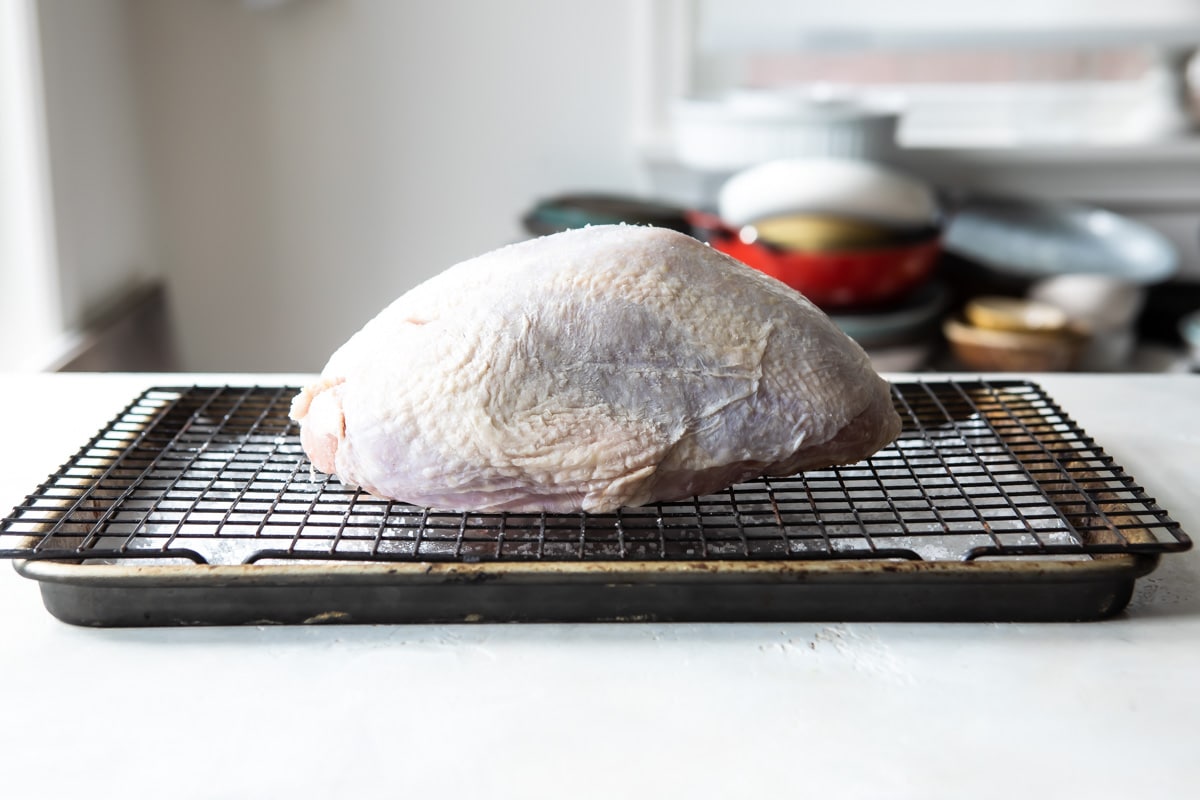 A raw turkey breast on a rack.