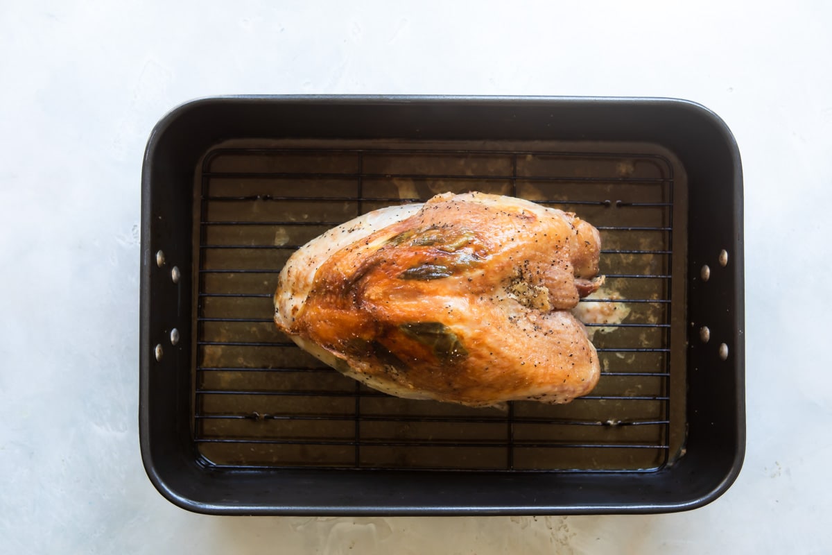 A roasted turkey breast in a roasting pan.