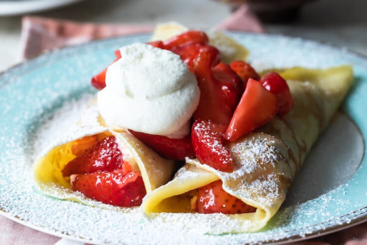 Strawberry crepes on a blue plate.