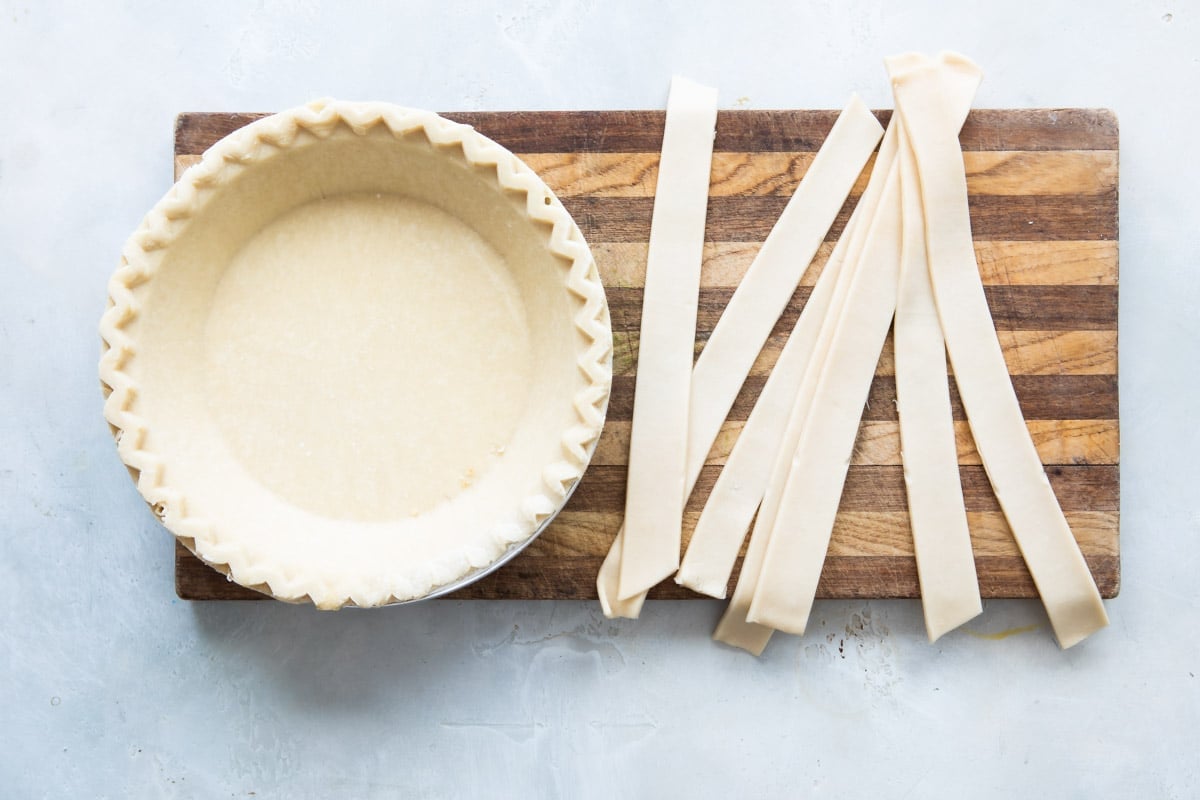 Pie crust and lattice pieces on a wooden cutting board.
