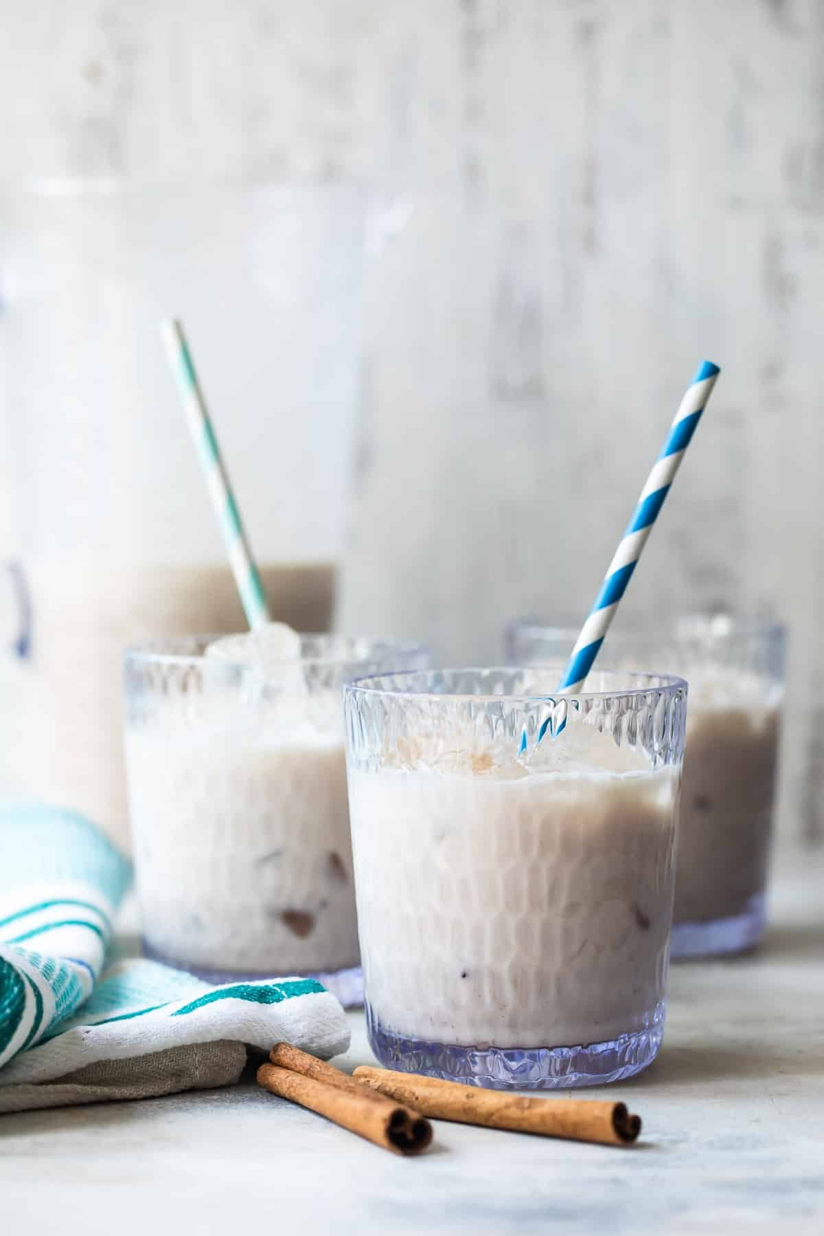 Glasses of cold agua de horchata with blue and white striped straws.