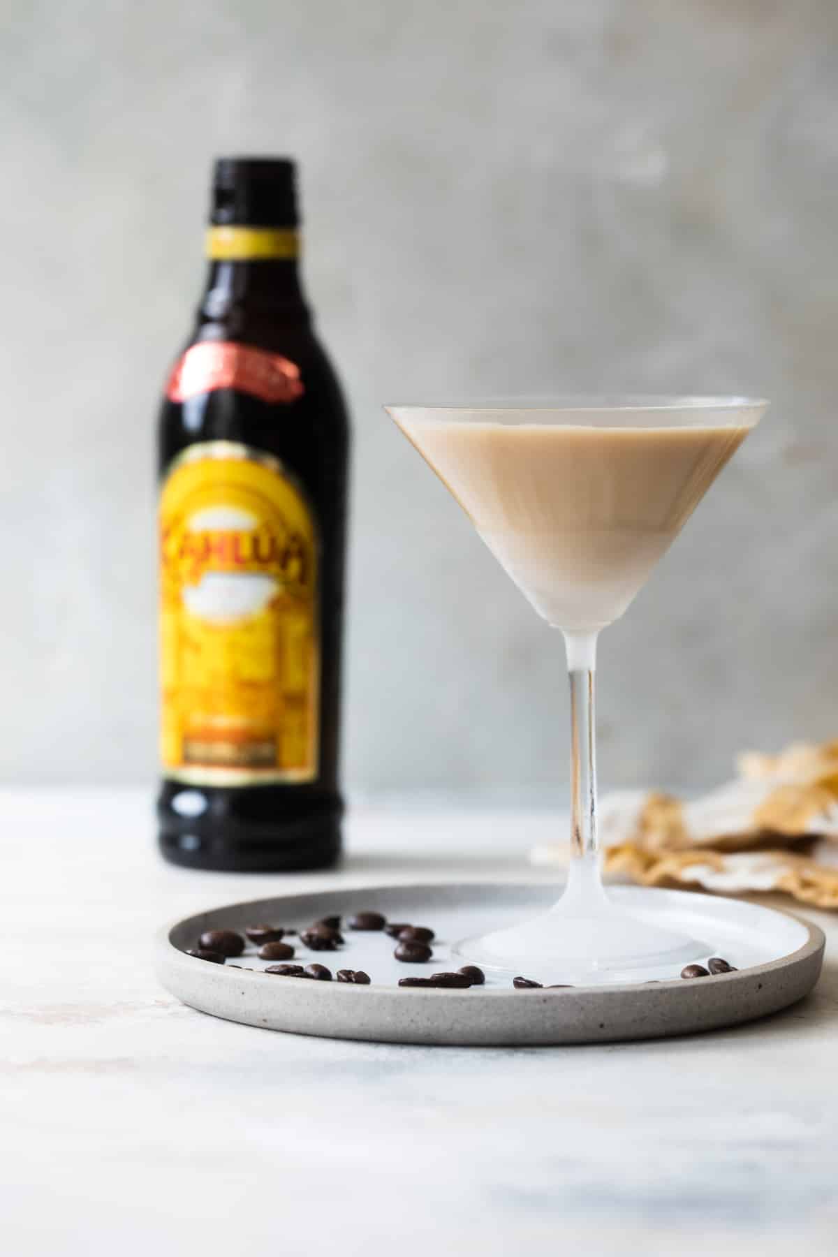 An espresso martini on a plate surrounded by espresso beans.