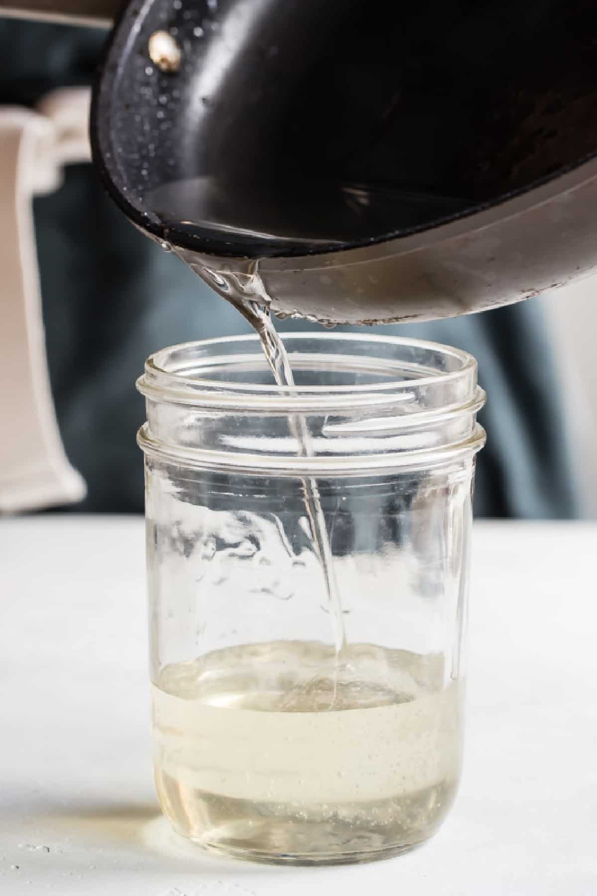 Pouring simple syrup into a jar.