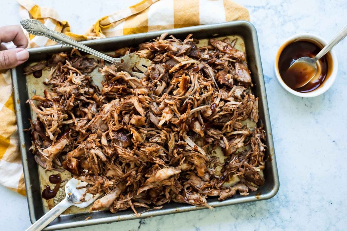 A sheet pan of cooked pulled pork.