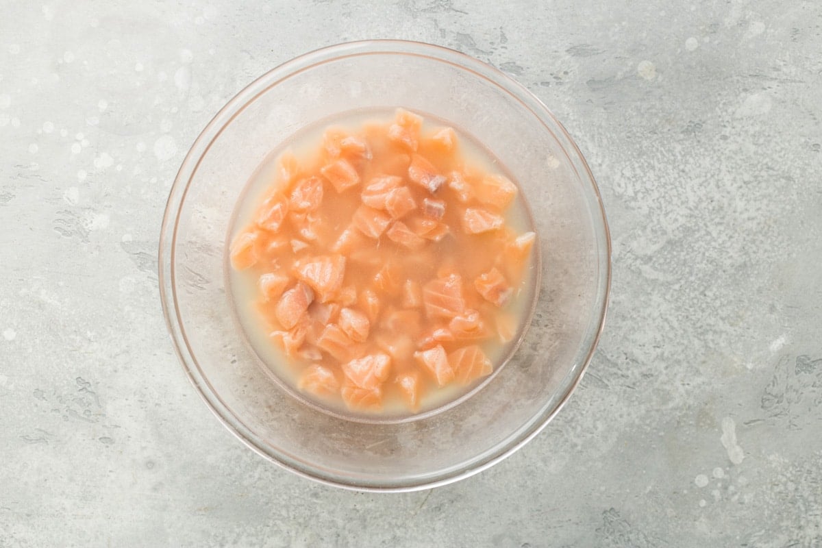 An overhead shot of salmon ceviche ingredients in a clear bowl.