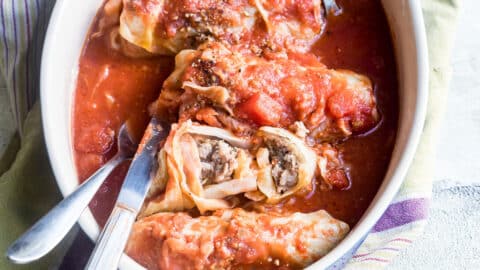 Stuffed cabbage rolls in a white baking dish.