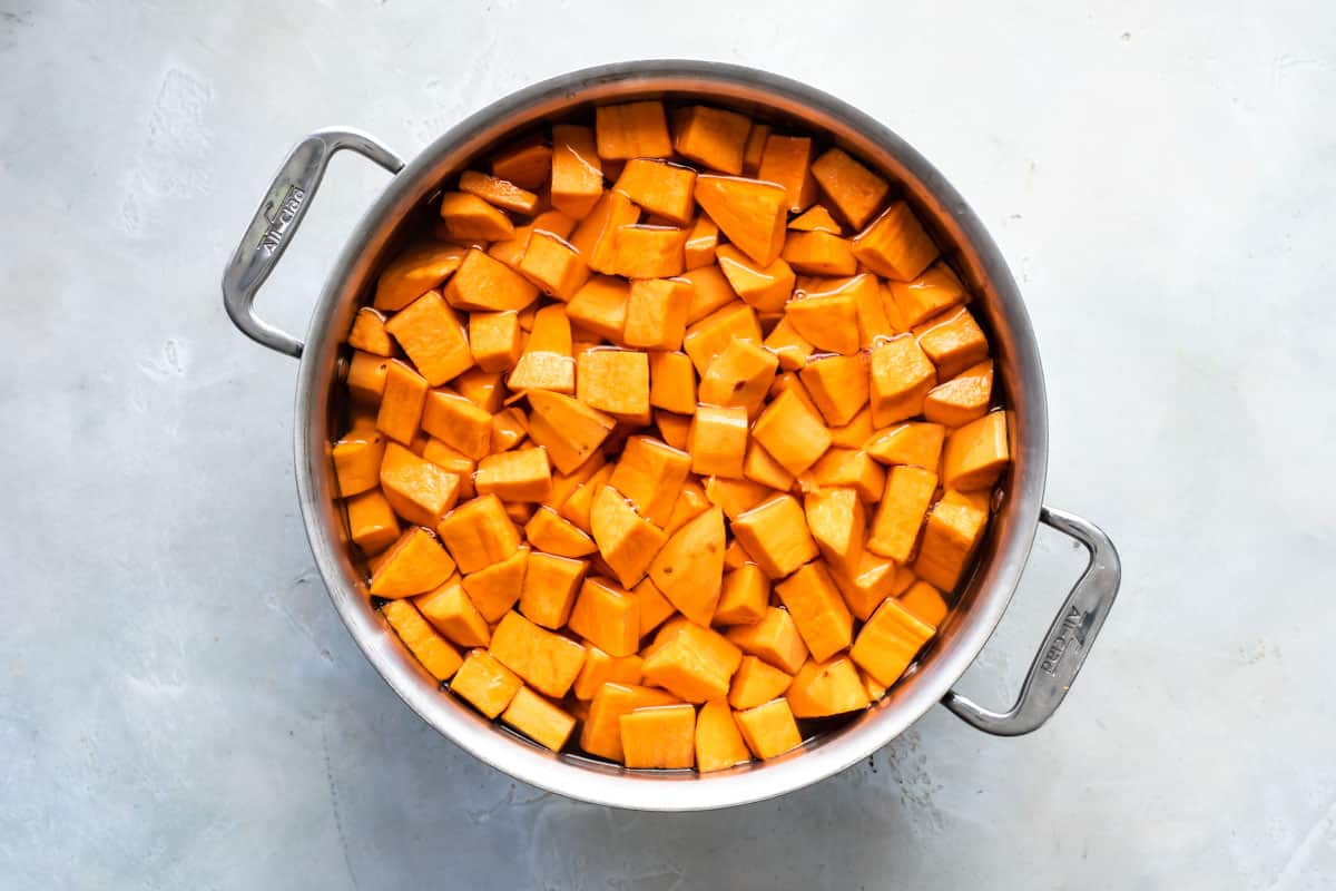 Cubed sweet potatoes in a silver pot with water.