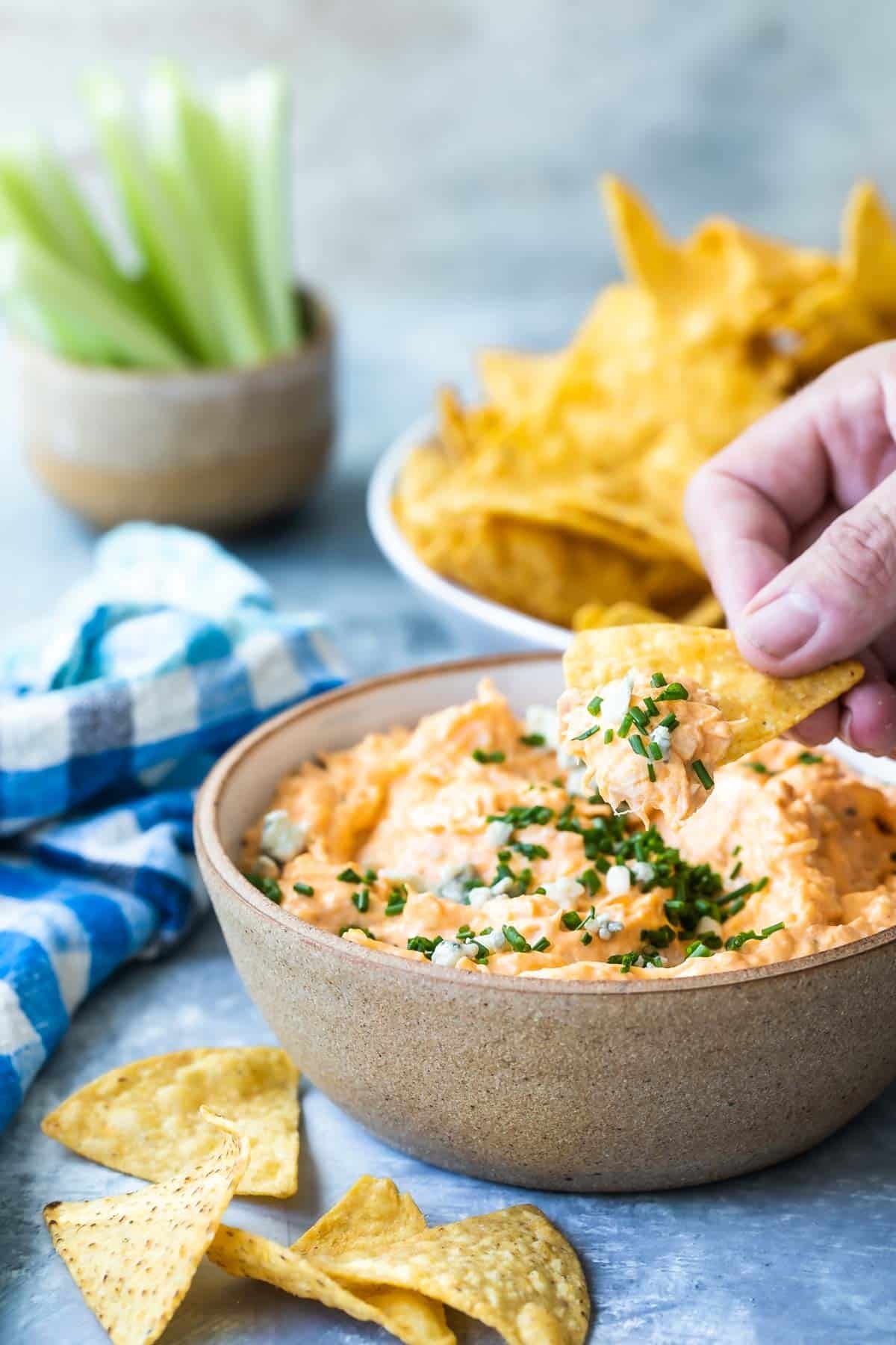 Buffalo chicken dip in a bowl with chips, crackers, and celery nearby.