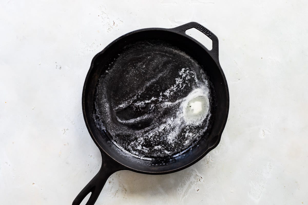 A cast iron skillet with melted butter in the bottom.