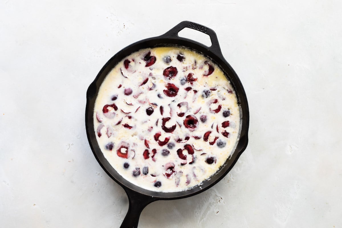 A cast iron skillet with unbaked Cherry Clafoutis.
