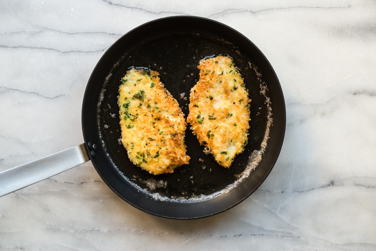 A skillet with chicken piccata frying.