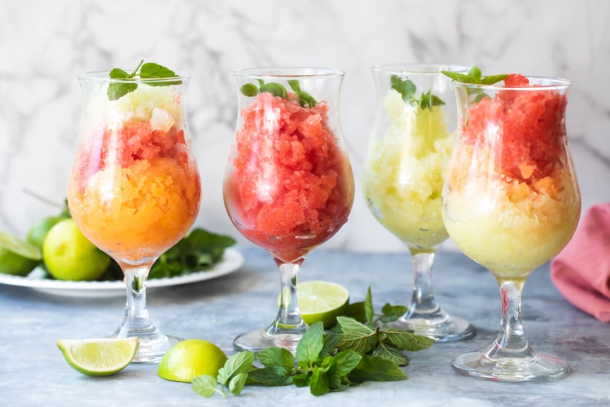 Glasses of cantaloupe, honey dew, and watermelon granita garnished with limes and mint.