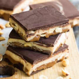 Homemade Snickers bars on a wooden cutting board.