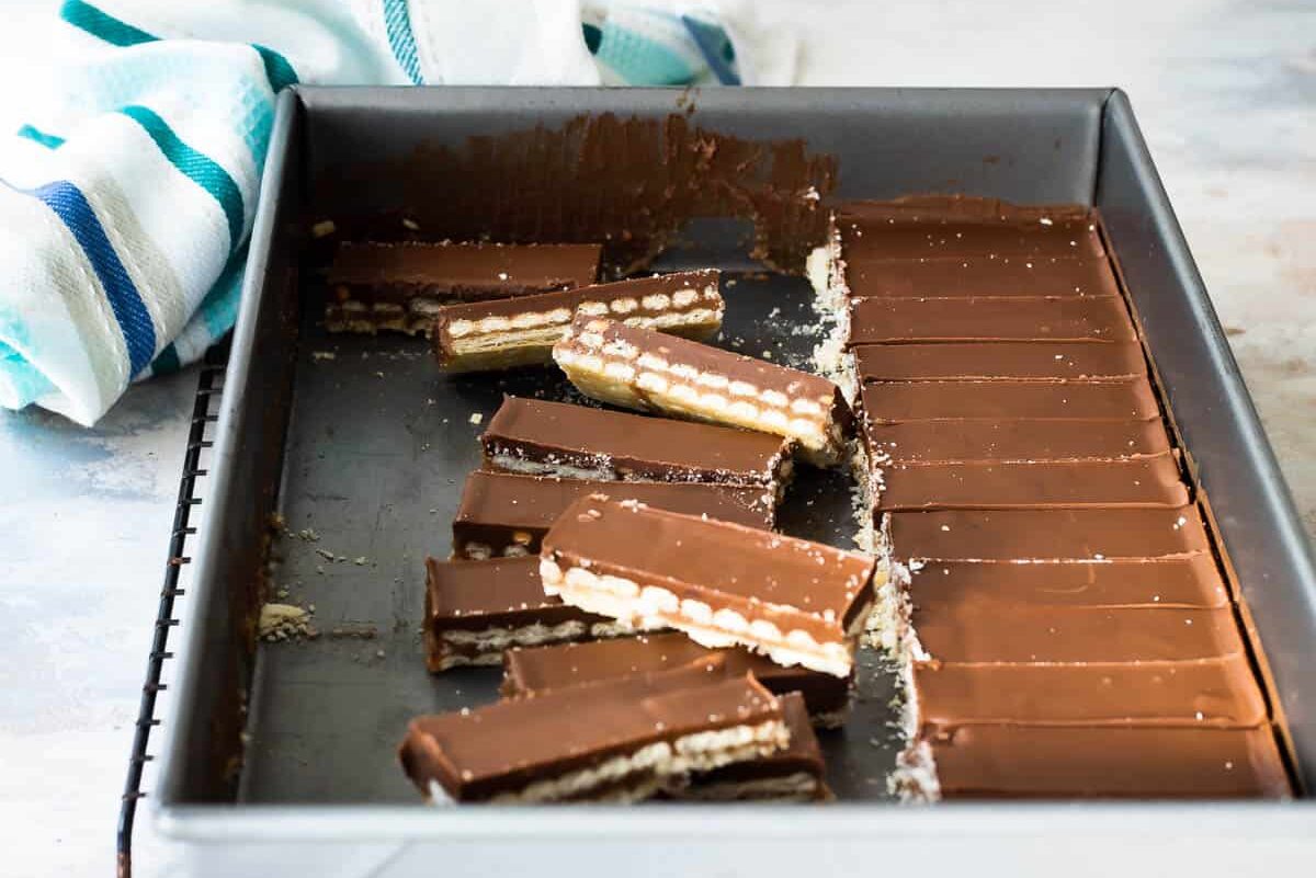 A baking pan filled with neat slices of homemade twix bars (some turned up on end).