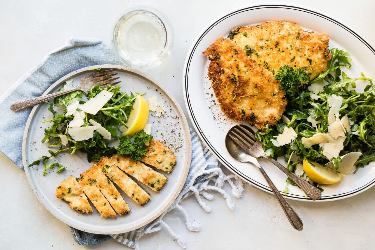 A plate with Chicken Milanese and arugula salad.