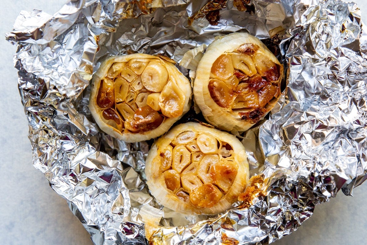 3 bulbs of roasted garlic in an open foil packet.