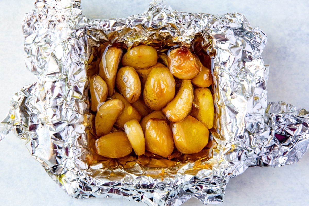 Roasted cloves of garlic drizzled with oil in a foil packet.