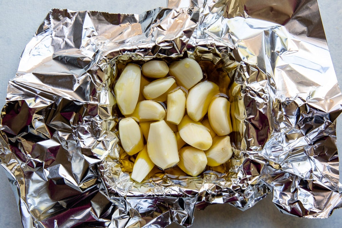 Raw cloves of garlic drizzled with oil in a foil packet.