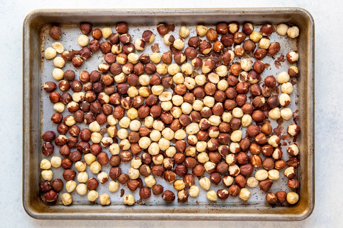 Raw hazelnuts on a baking sheet.