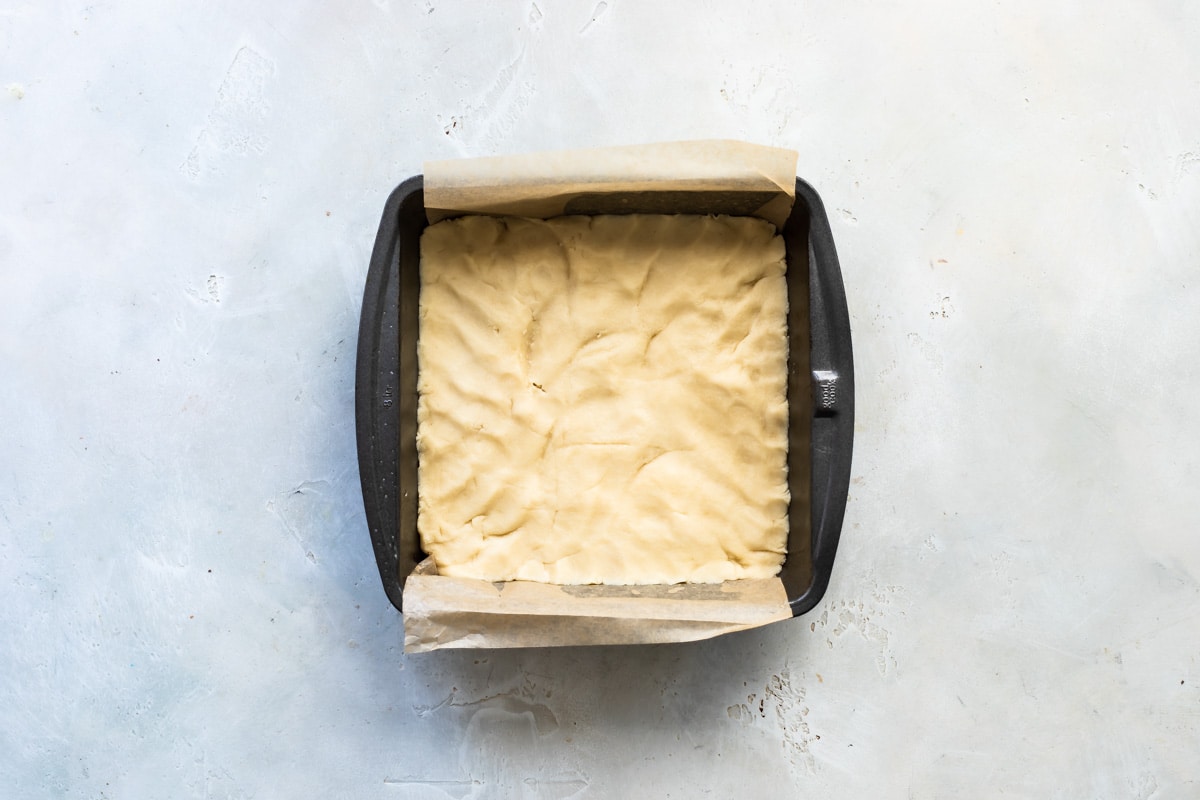 Unbaked dough for shortbread in a square pan.