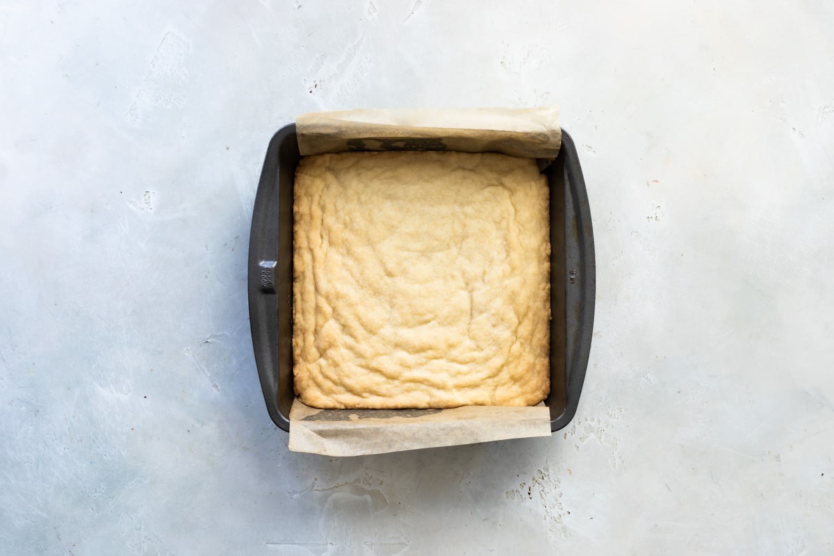 Shortbread crust in a square baking pan.