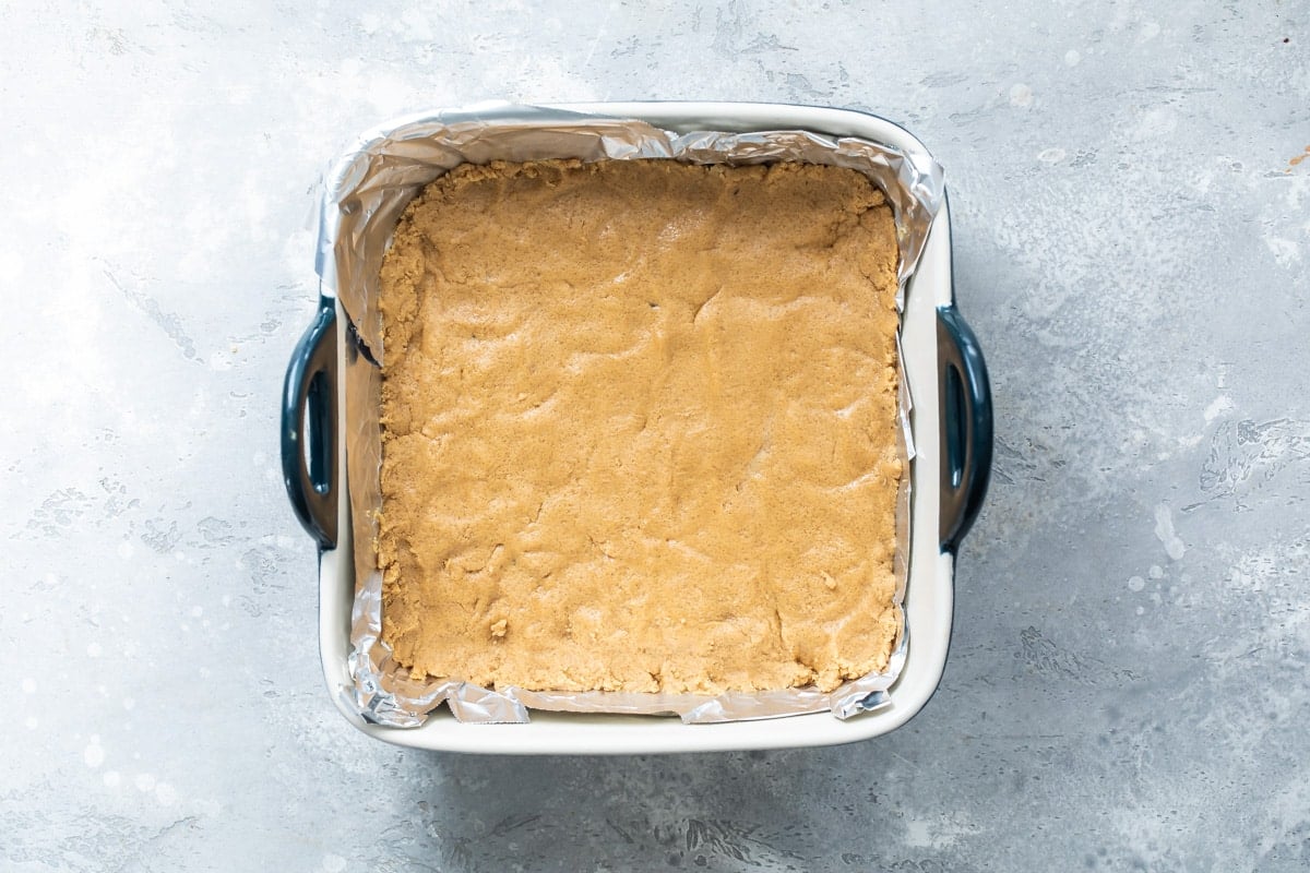 The filling of no-bake peanut butter bars pressed into a baking dish.