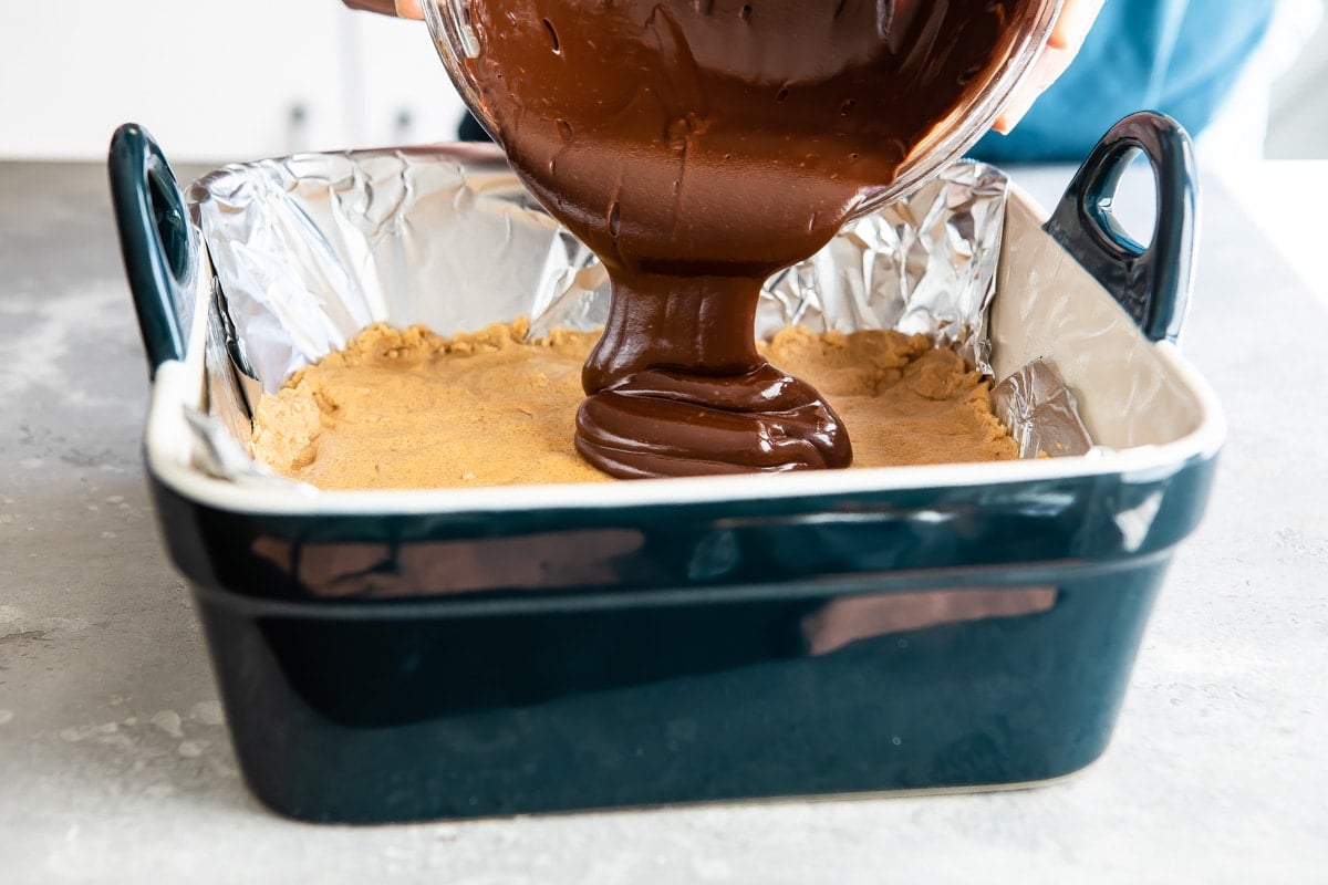 Drizzling melted chocolate over no-bake peanut butter bars.