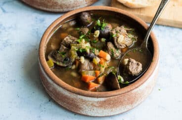 Slow cooker beef barley soup in a brown bowl.