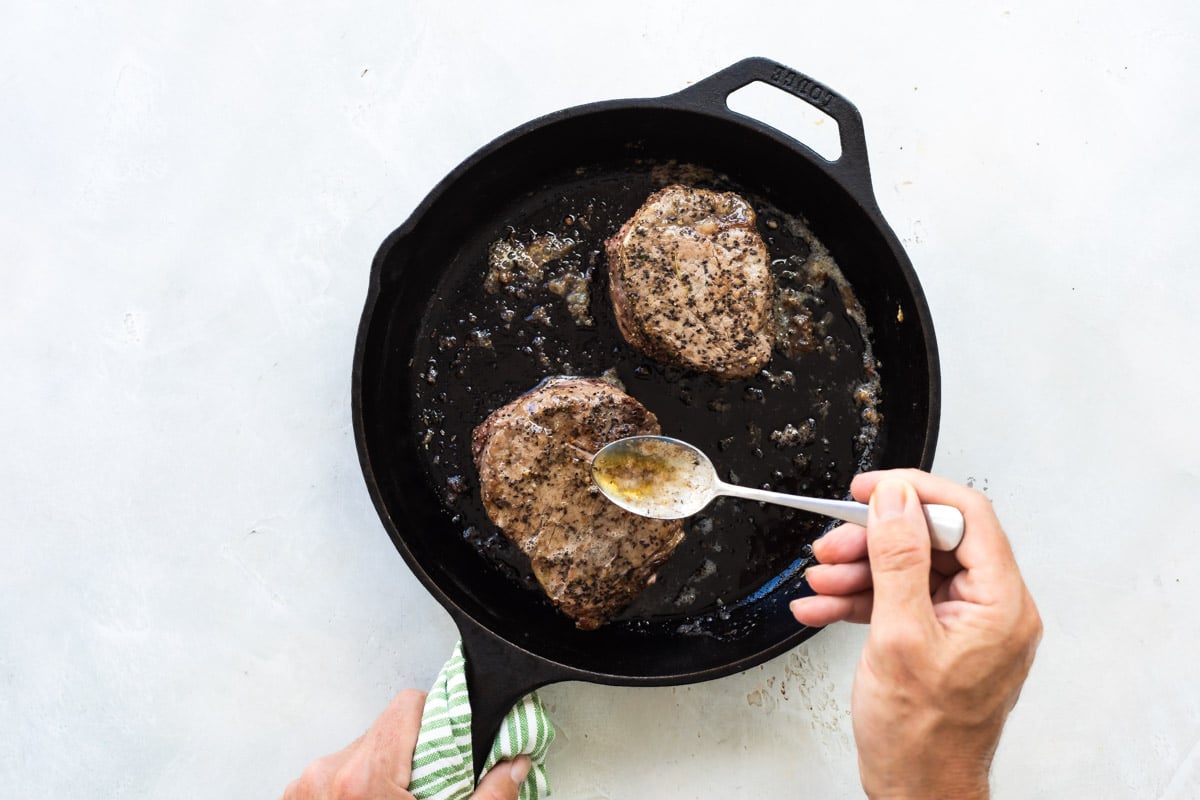 Searing filet mignons in a skillet.