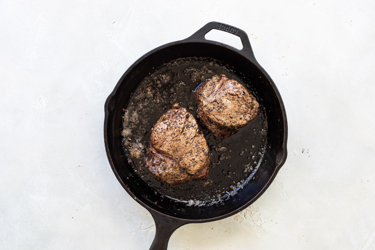Searing filet mignons in a skillet.