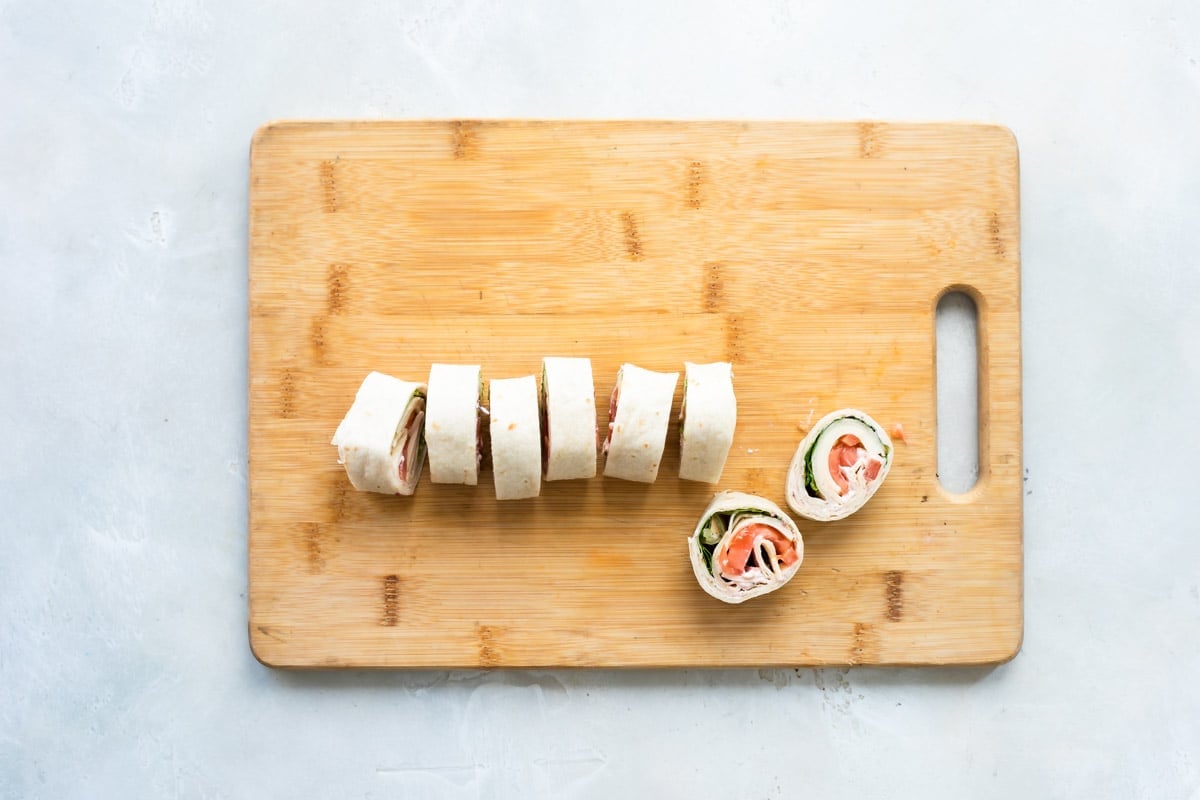 Slices of turkey roll ups on a wooden board.