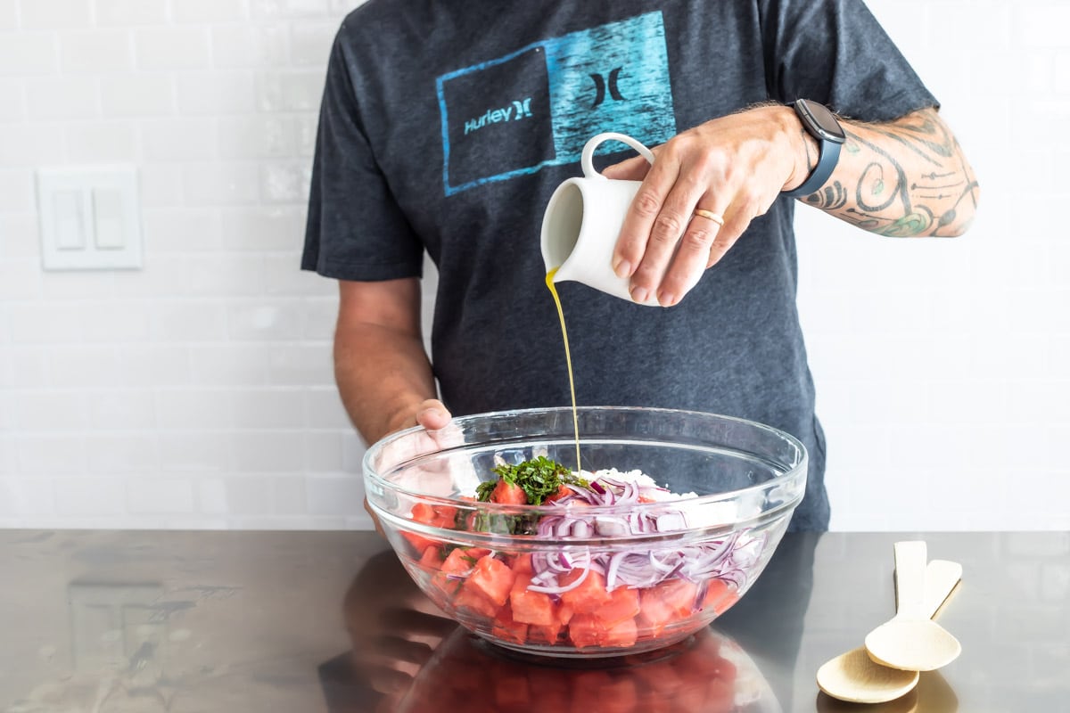 Assembling a watermelon salad in a glass bowl.