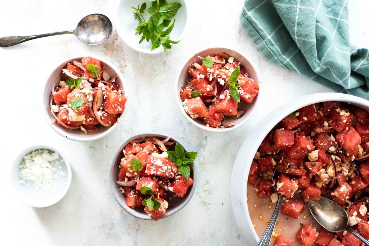 Small bowls of watermelon salad with feta cheese and mint on top.