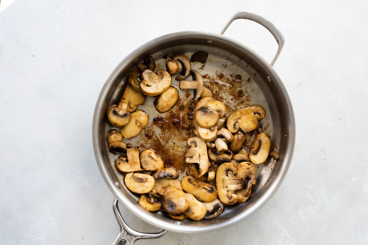 Cooking mushrooms and shallots in a skillet.