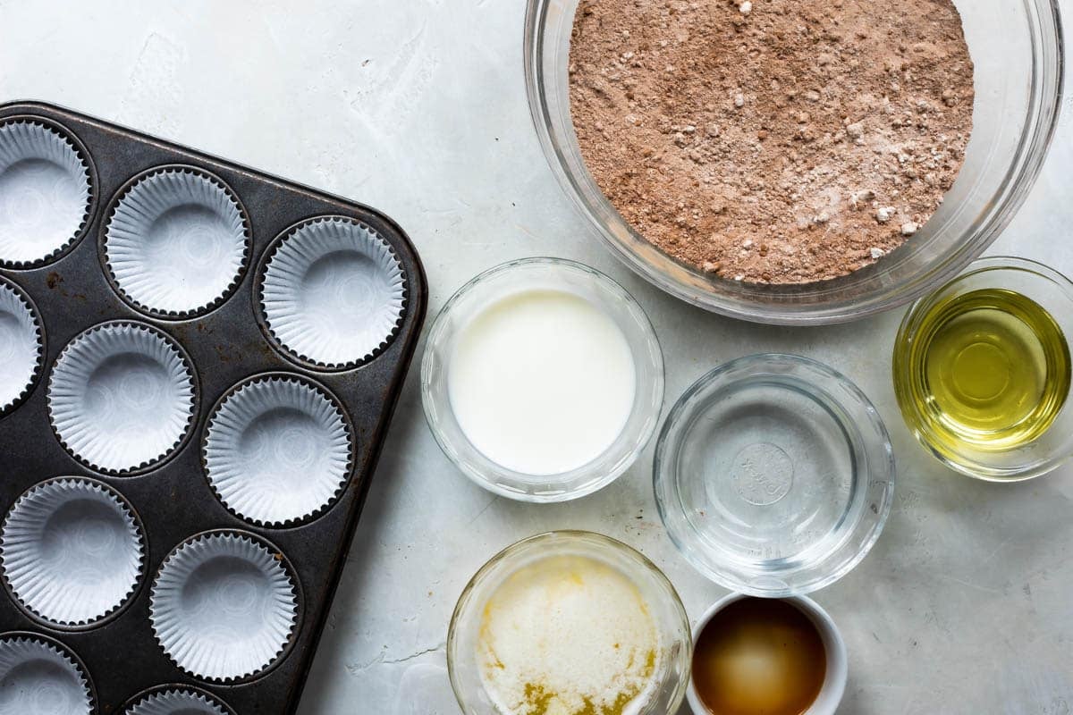 A lined muffin tin next to the ingredients for chocolate cupcakes.