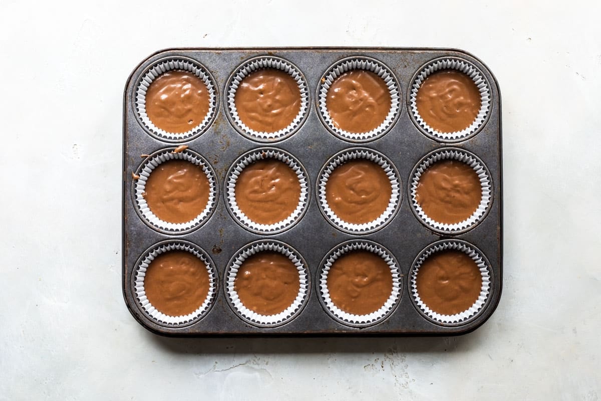 Chocolate cupcake batter divided in a muffin tin.